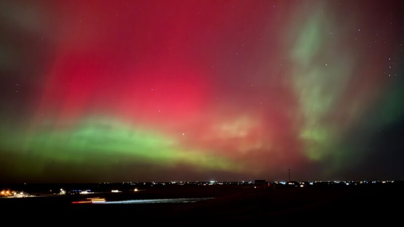 Wide view of the sky, with red and green colors. There are some white dots for the stars. Sun news.