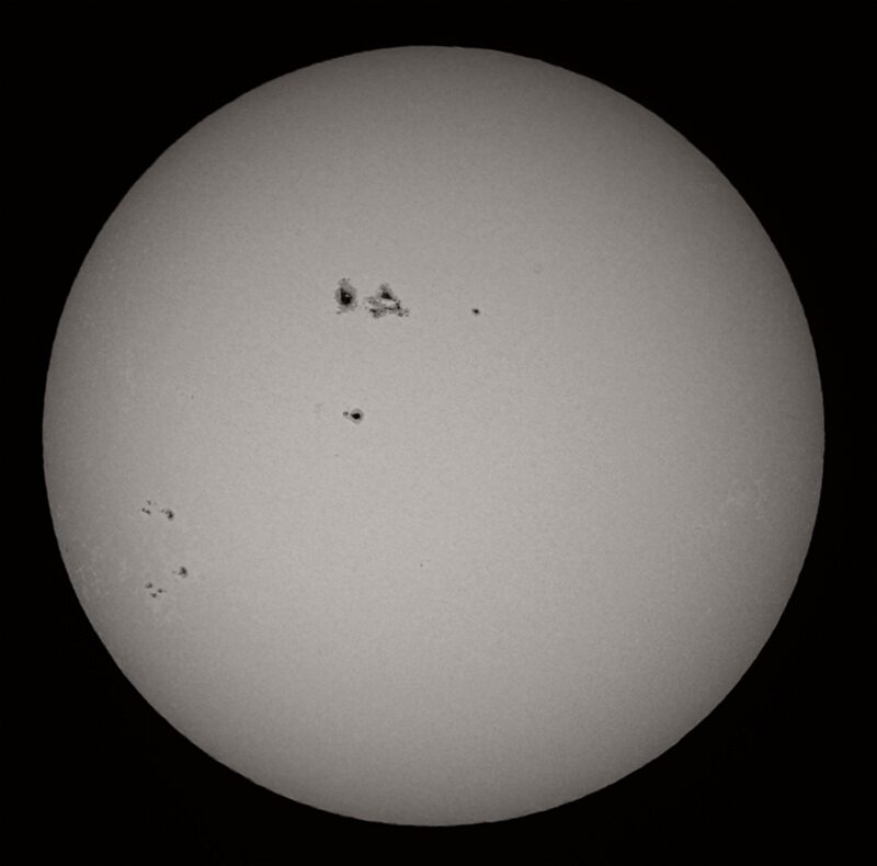 The sun, seen as a large gray sphere with small dark spots.