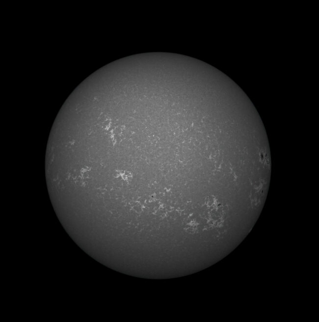 The sun, seen as a large gray sphere with a mottled surface.