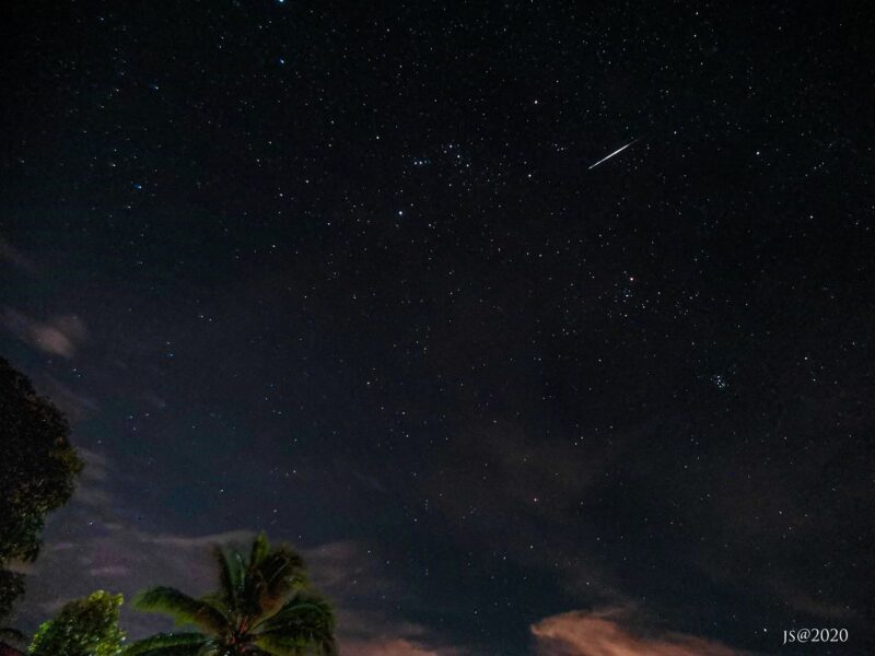 Starry sky with stars of Orion and a short, bright streak next to them.