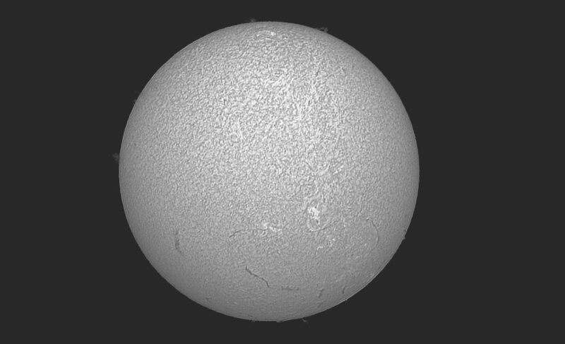The sun, seen as a large gray sphere with a mottled surface.