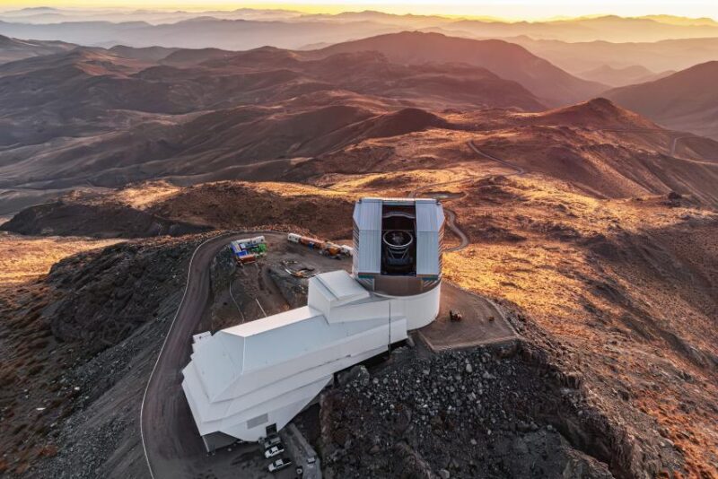 A white telescope dome and buildings sit atop a parched landscape.