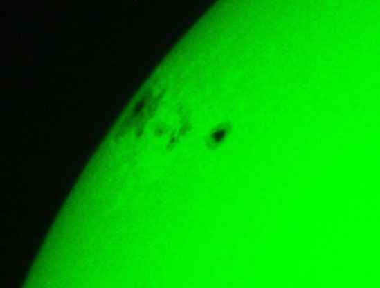 The sun, seen as a green sectional sphere with dark spots.