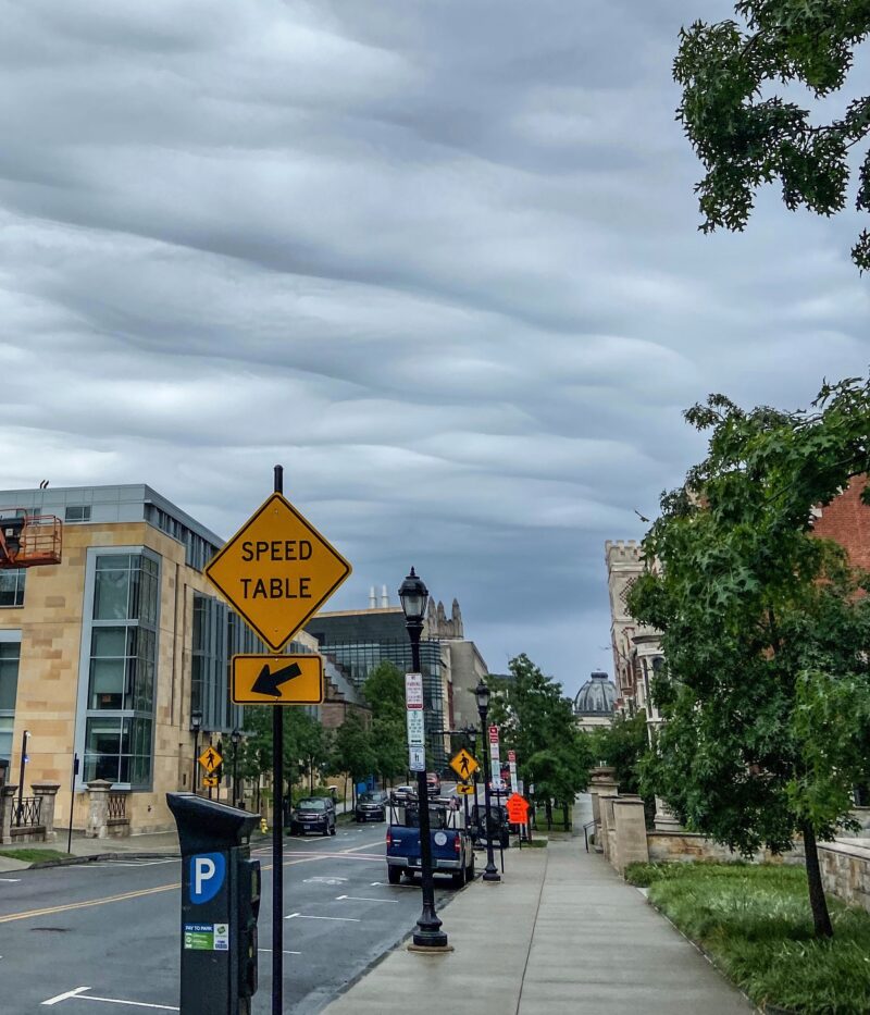 A city scene with undulating clouds above.