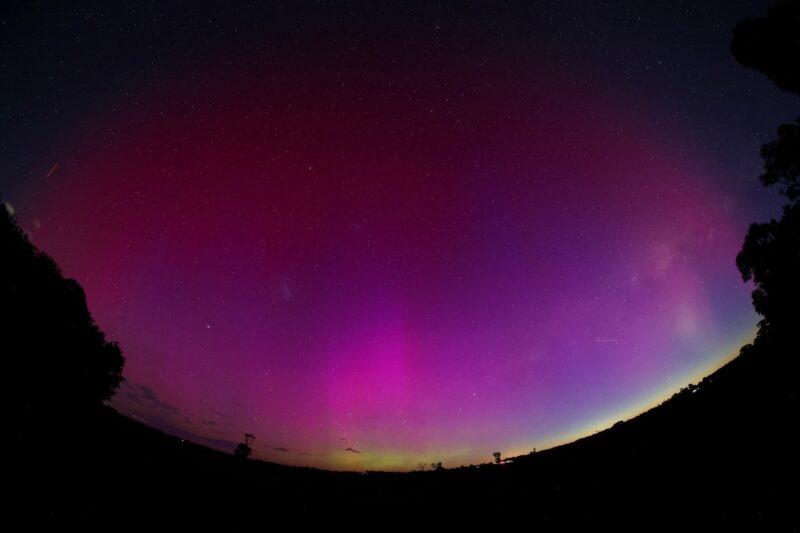 Aurora showing purple and pink rays with light green on the horizon.