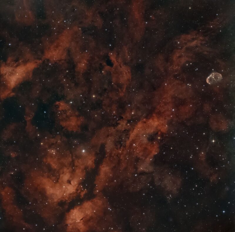 Multiple orange clouds with dark lanes in between, plus numerous faint stars.