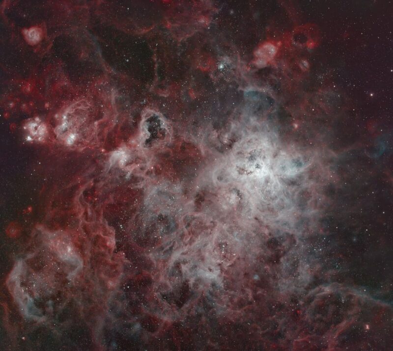 Deep-sky photos: A complex structure of red and pink gas overlaid with dark nebulae, with numerous background stars.
