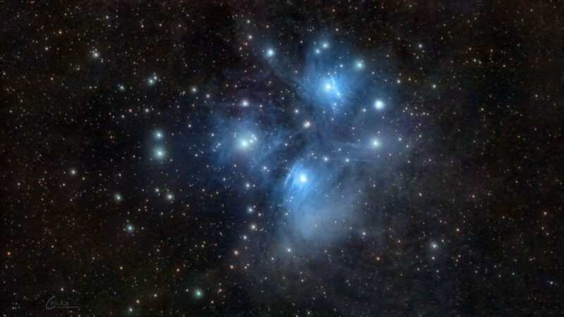 A large area of electric blue nebulosity with bright white stars immersed within.