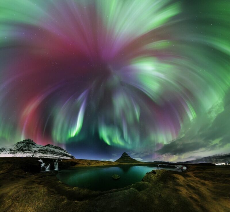 Northern lights photos: Green and red aurora seeming to emanate from one point and burst like a firework over a cold landscape.