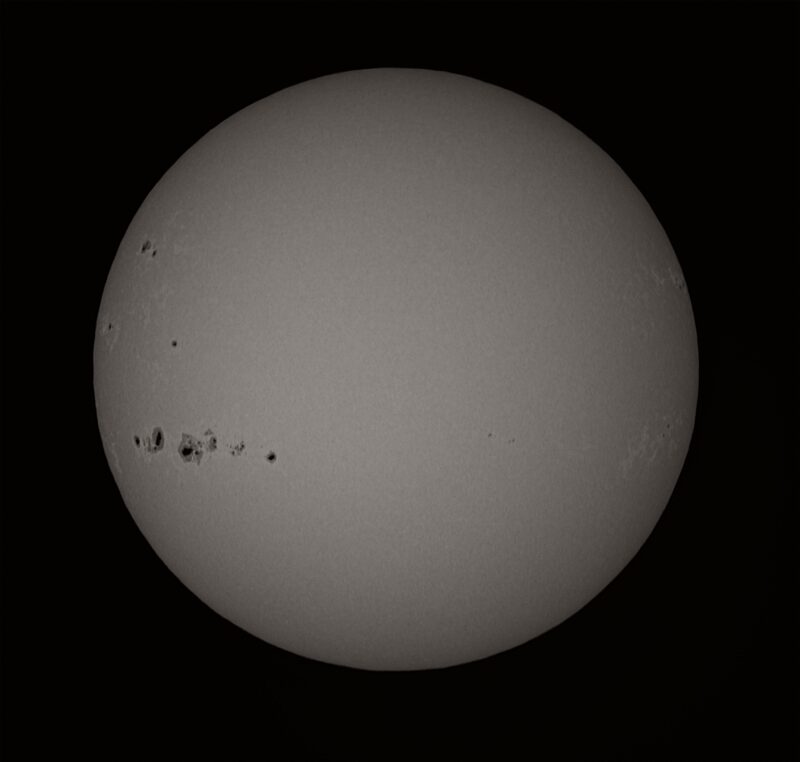 The sun, seen as a large gray sphere with small dark spots.