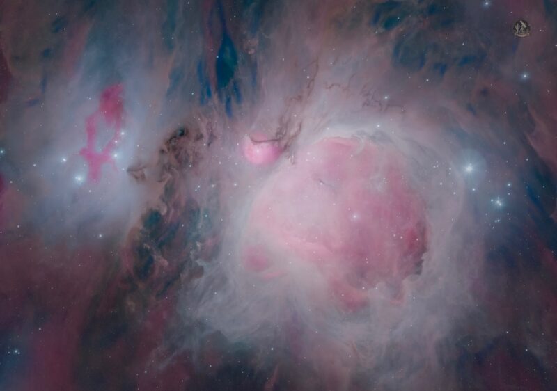 Large, expansive cloud of pink gas with a small dark patches and scattered background stars.