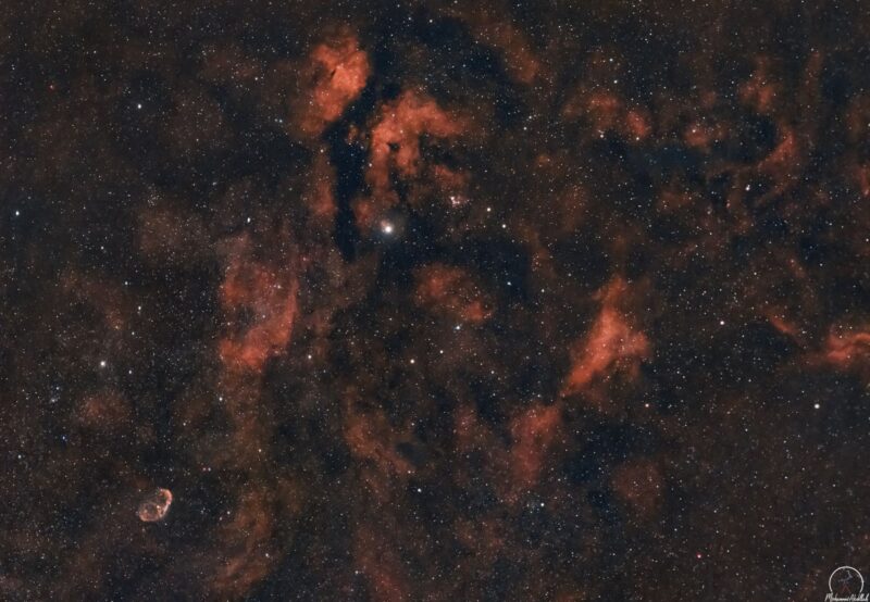 A complex of red nebulous patches with a numerous faint background stars.
