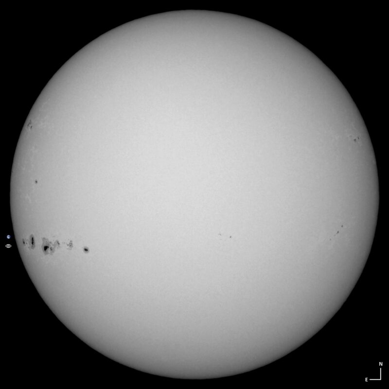 The sun, seen as a large white sphere with small dark spots.