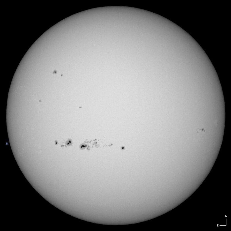The sun, seen as a large white sphere with small dark spots.
