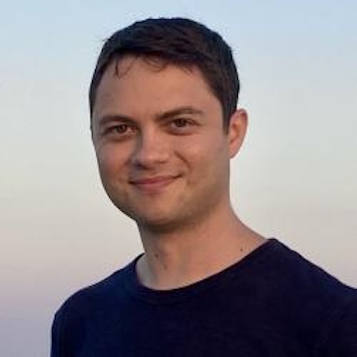 Smiling man with short hair wearing a dark t-shirt.