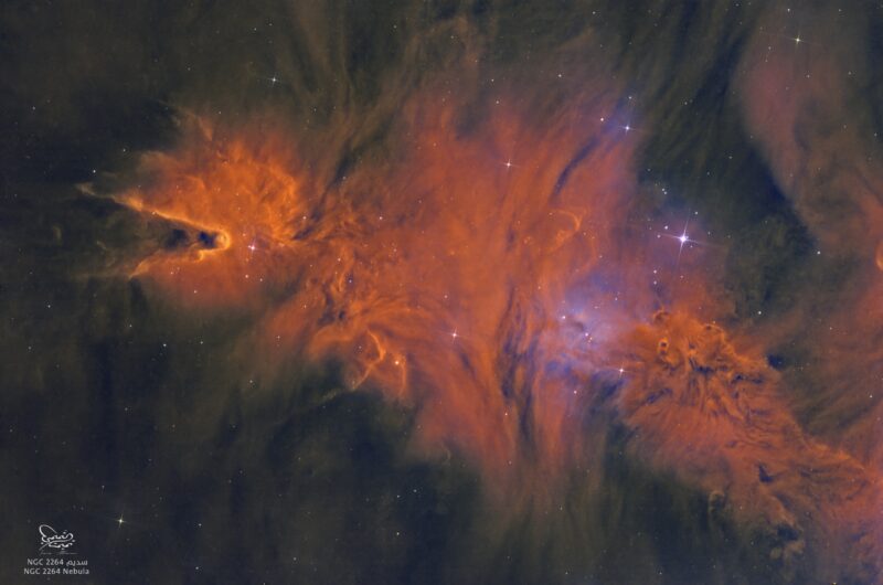 A large area of orange nebulosity with a cone-shaped dark indentation, with sparse stars immersed within.