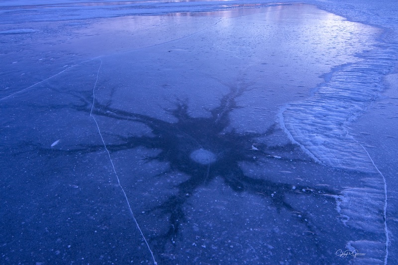 Тамни кружни отвор у леду са много пукотина попут ногу које зраче из њега.