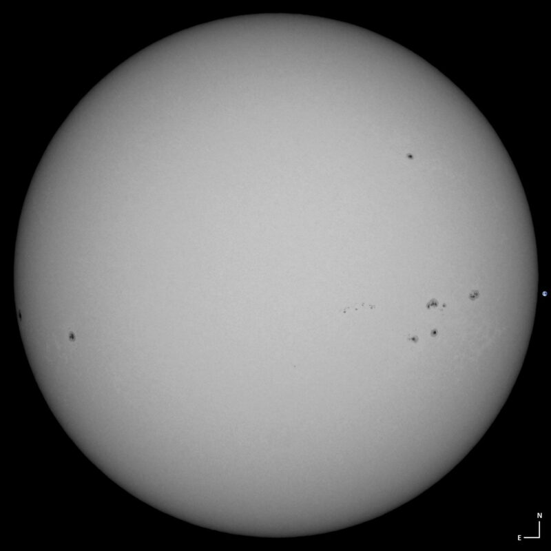 The sun, seen as a large white sphere with small dark spots.