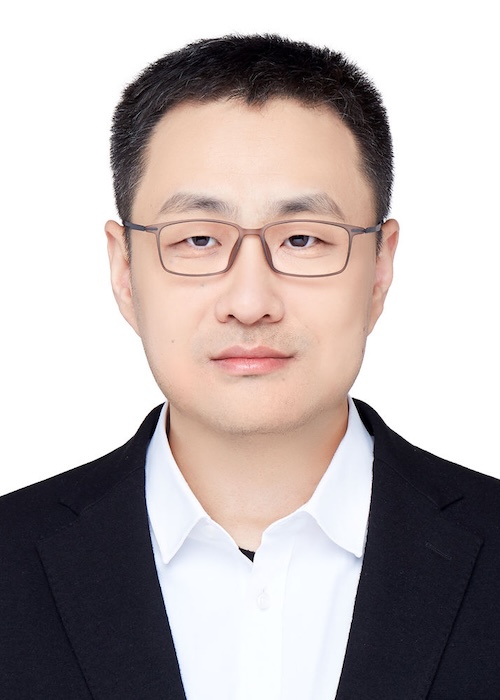 Man with short dark hair and eyeglasses wearing a black suit jacket.