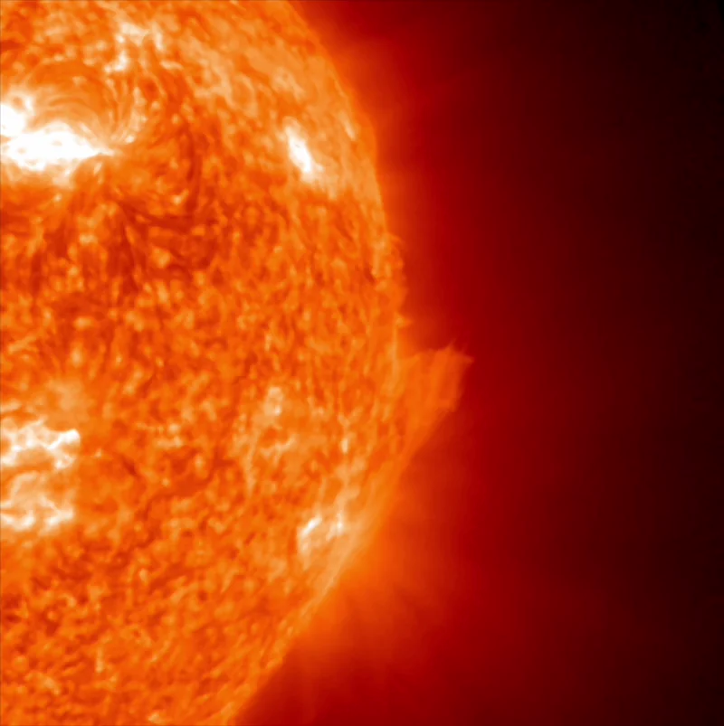 View of the sun with bright spots and glowing gases rising along one edge.