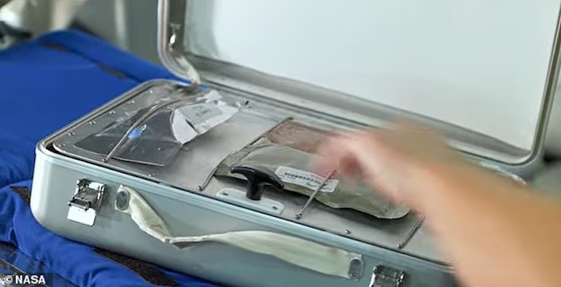 A hand placing a packet into a small case-like device with its lid open.
