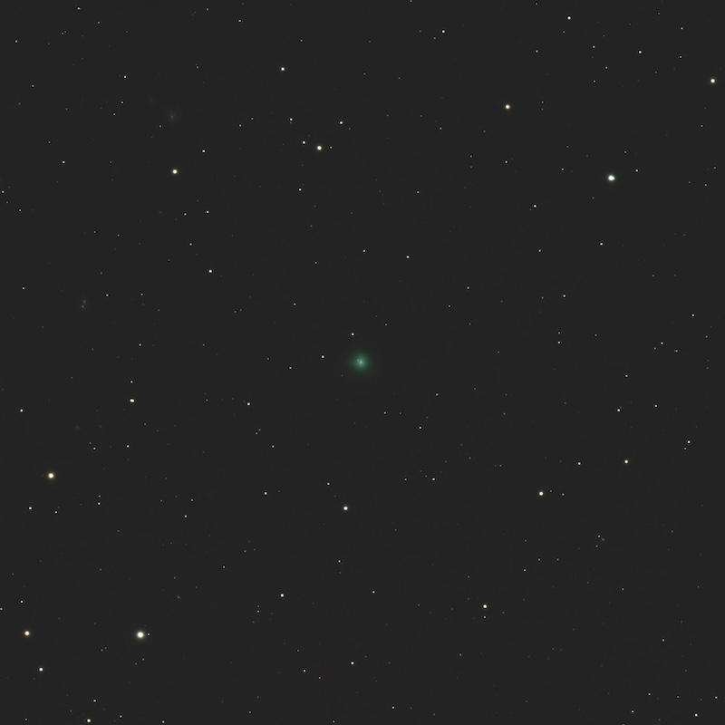 Small, dim, fuzzy ,green spot centered on a field of stars.