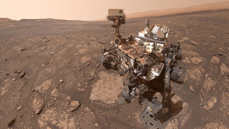 Organics on Mars: Mechanical rover sitting in  brownish, rocky terrain, with dusty sky above.