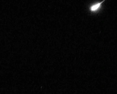 Blazing meteor expanding to fireball as it flies from top right to bottom left.