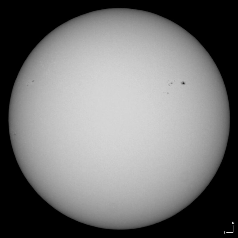 The sun, seen as a large white sphere with small dark spots.