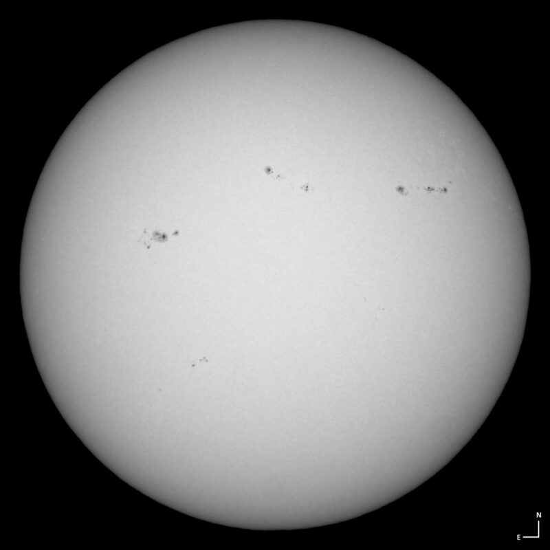 The sun, seen as a large white sphere with small dark spots.