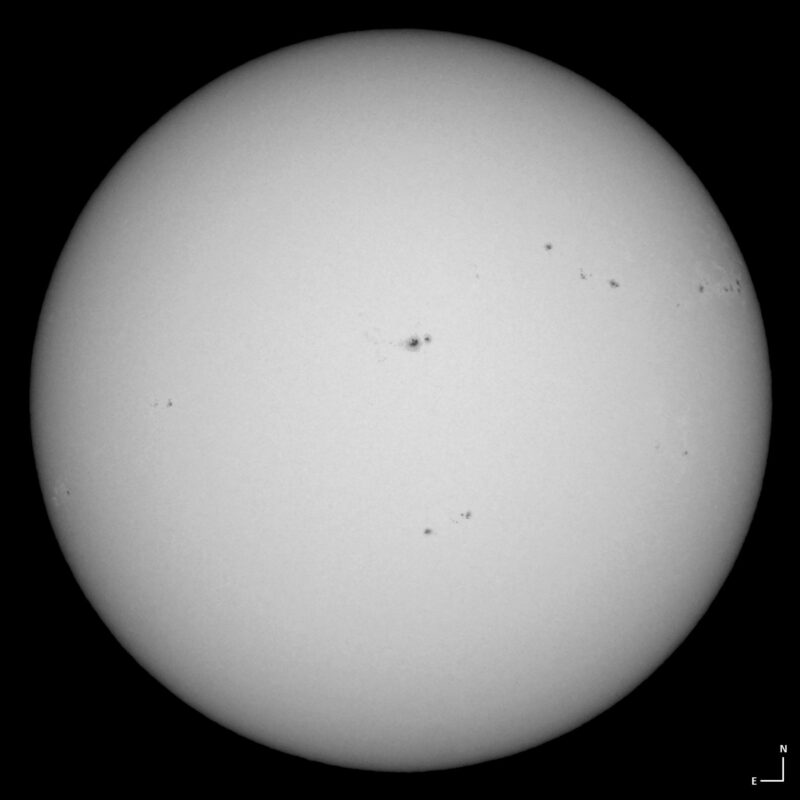 The sun, seen as a large white sphere with small dark spots.