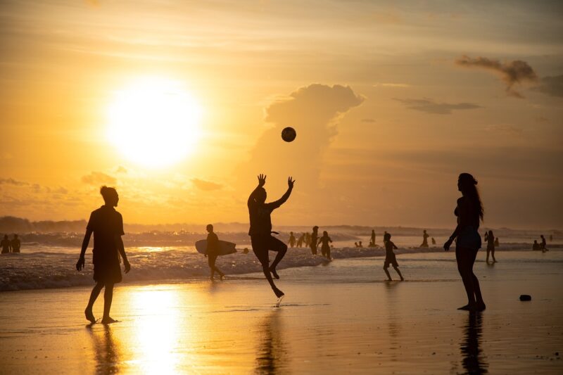 Super El Niño: People surfing and playing volleyball on a beach beneath a blazing afternoon sun.