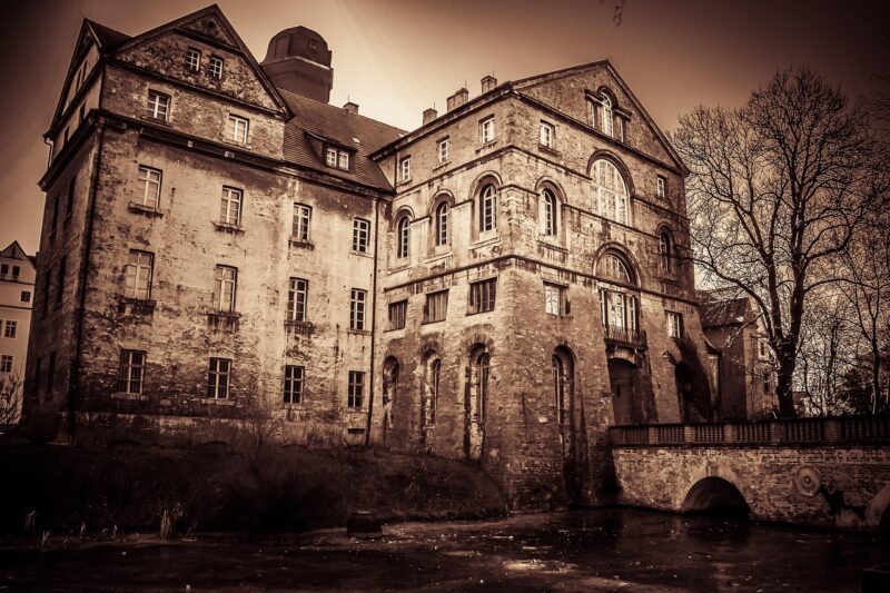 A sepia-toned photo of a very large, old, spooky-looking house.