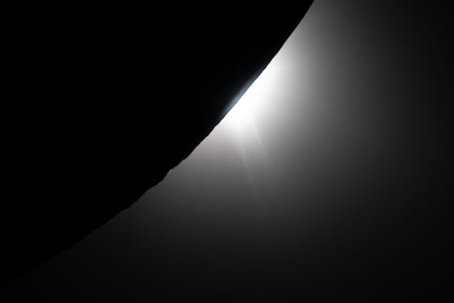 Closeup of the edge of the moon with some roughness and a bright glow at one spot.