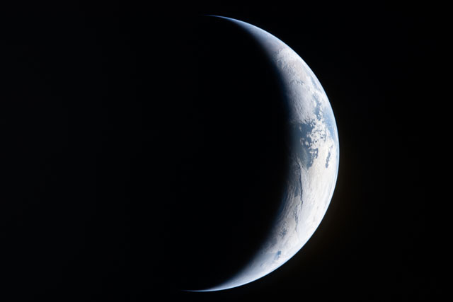 Sharp blue and white crescent Earth lit on the right side.