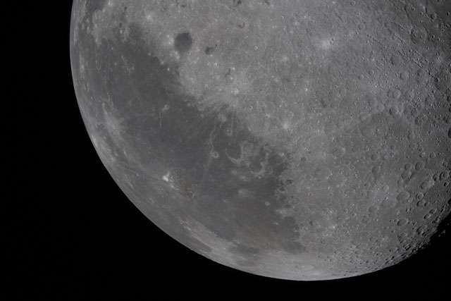 12,000 Artemis pics: Part of the moon with many craters and some dark areas with irregular outlines.