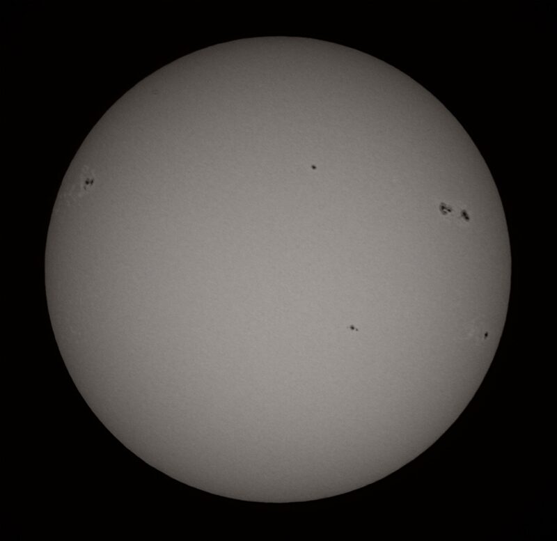 The sun, seen as a large gray sphere with small dark spots.