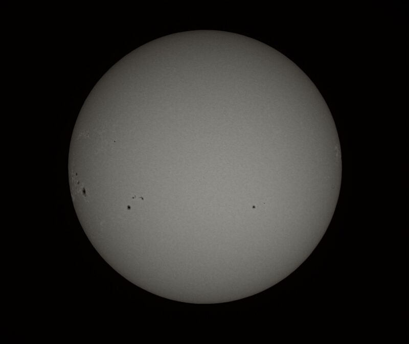 The sun, seen as a large gray sphere with small dark spots.