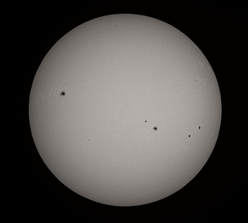 The sun, seen as a large gray sphere with small dark spots.
