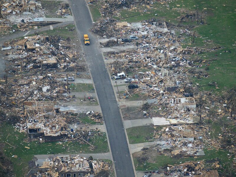 Joplin tornado damage with shredded houses all up and down a street with one vehicle in the street.