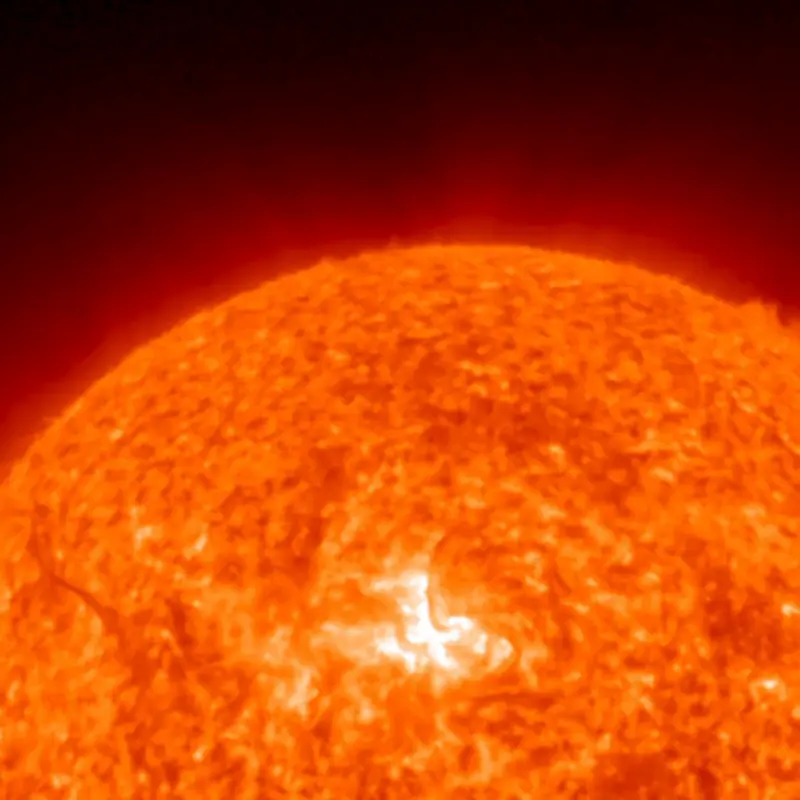 Sun, with threads of gas bursting forth from a glowing spot on it.
