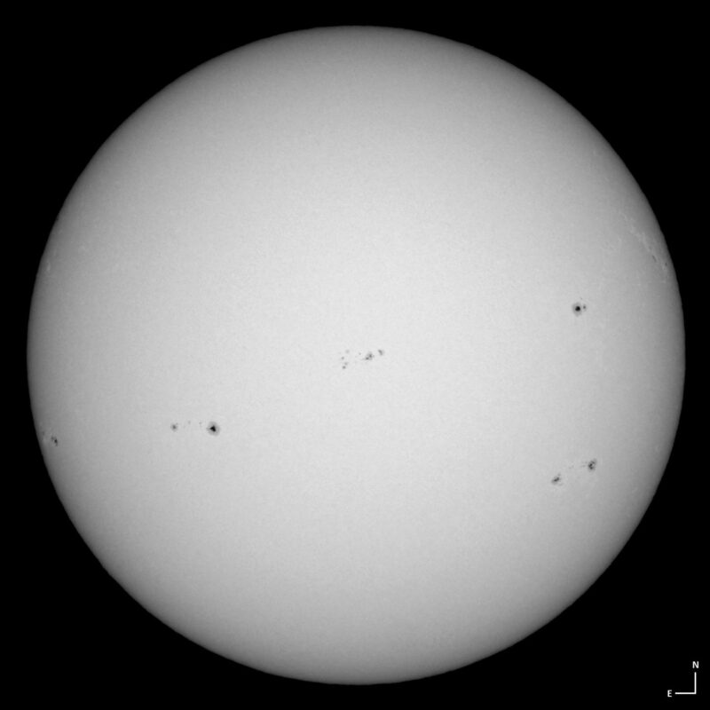 The sun, seen as a large white sphere with small dark spots.