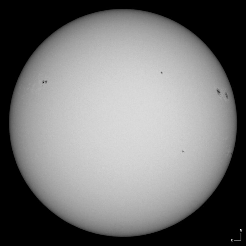 The sun, seen as a large white sphere with small dark spots.