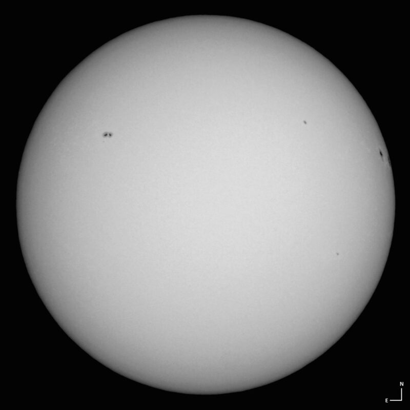 The sun, seen as a large white sphere with small dark spots.