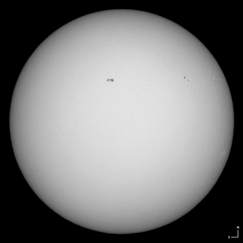 The sun, seen as a large white sphere with small dark spots.