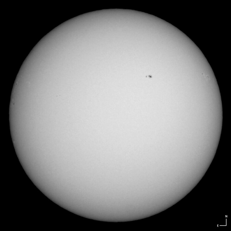 The sun, seen as a large white sphere with small dark spots.