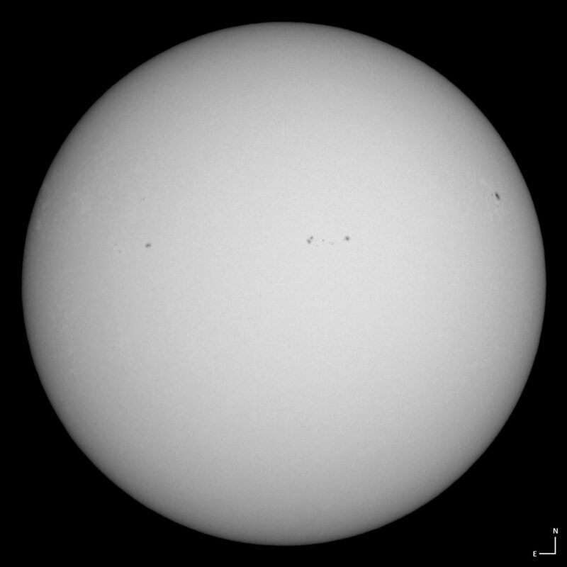 The sun, seen as a large white sphere with small dark spots.