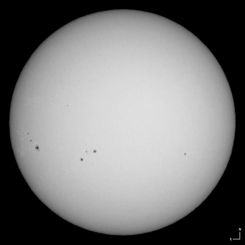 The sun, seen as a large white sphere with small dark spots.