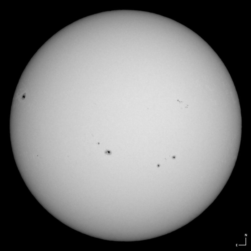 The sun, seen as a large white sphere with small dark spots.