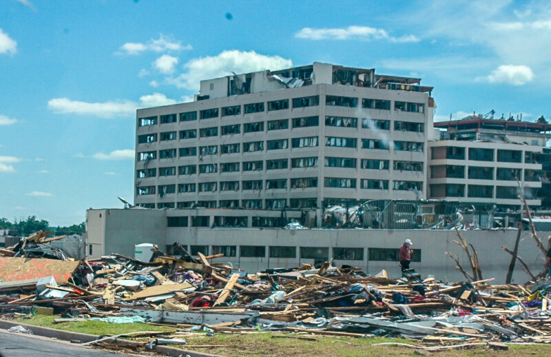 10-story rectangular building with windows blown out and much interior damage, near completely destroyed building.